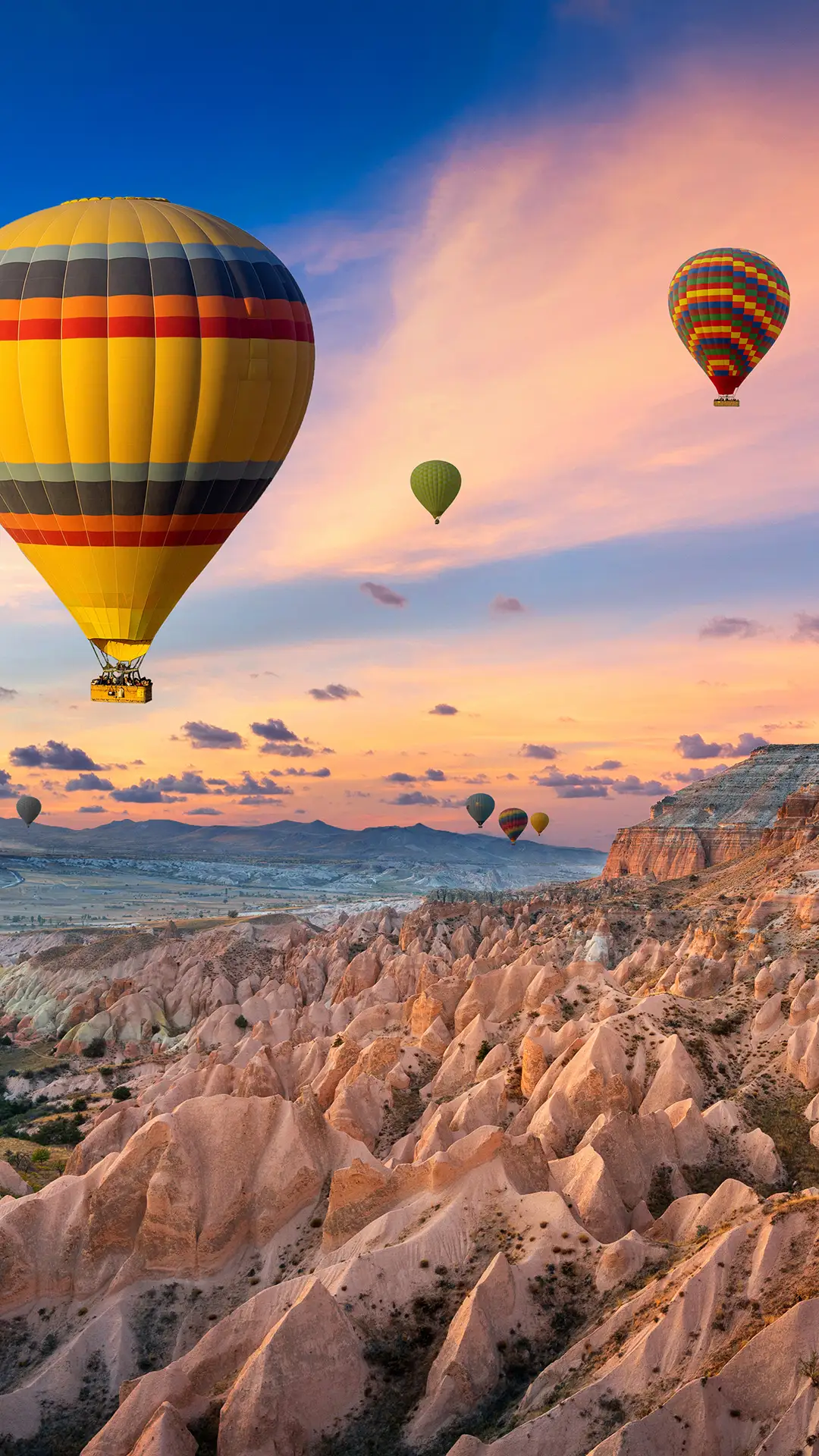 Hot air balloons and Red valley at sunset in Goreme, Cappadocia in Turkey.