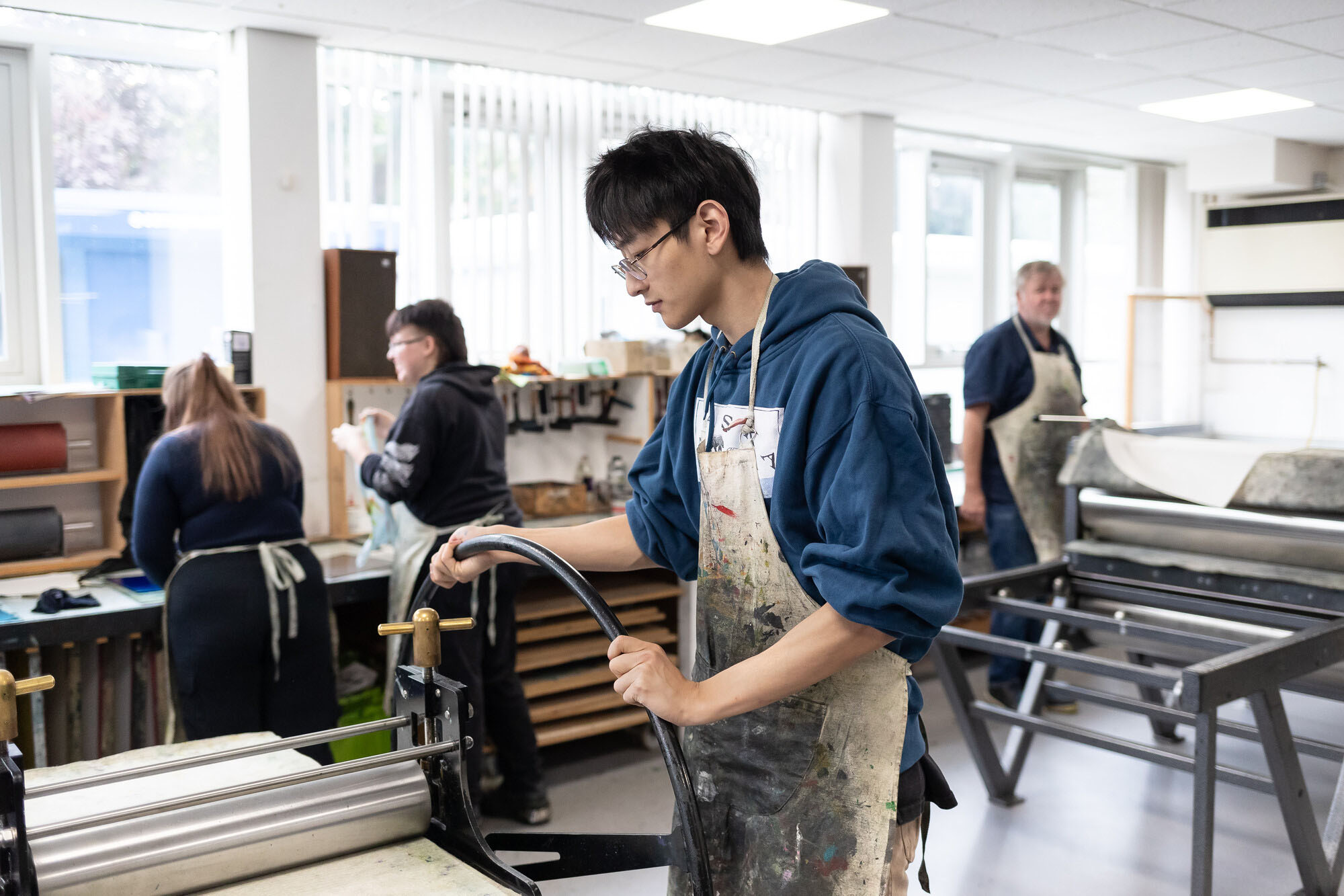 Student in Art and Design print room operating a roller