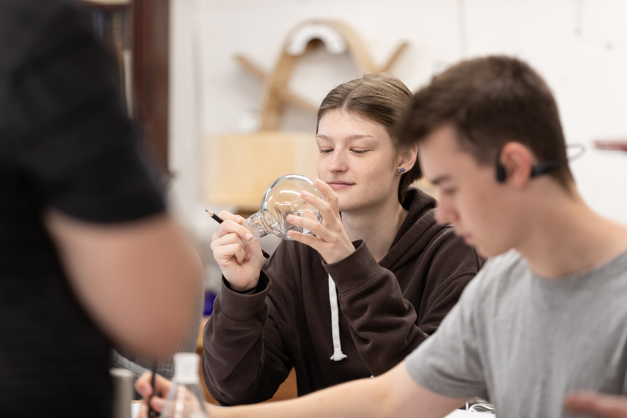 Student holding a globe shaped glass and pencil