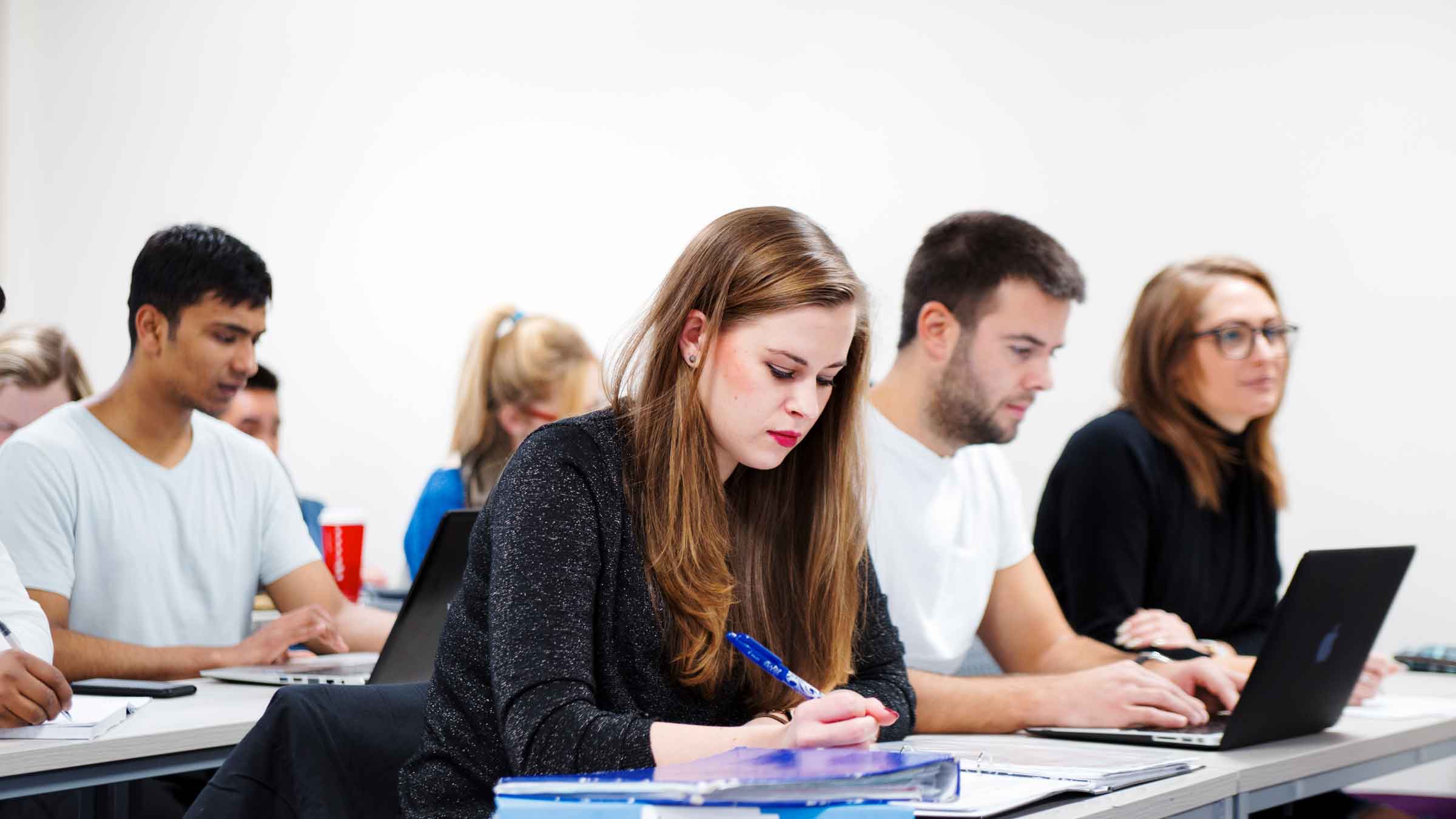 A group of students working at desks in a lecture room
