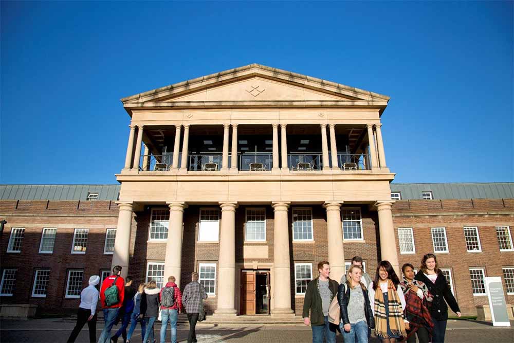 A group of students walking outside in front of Churchill House entrance.