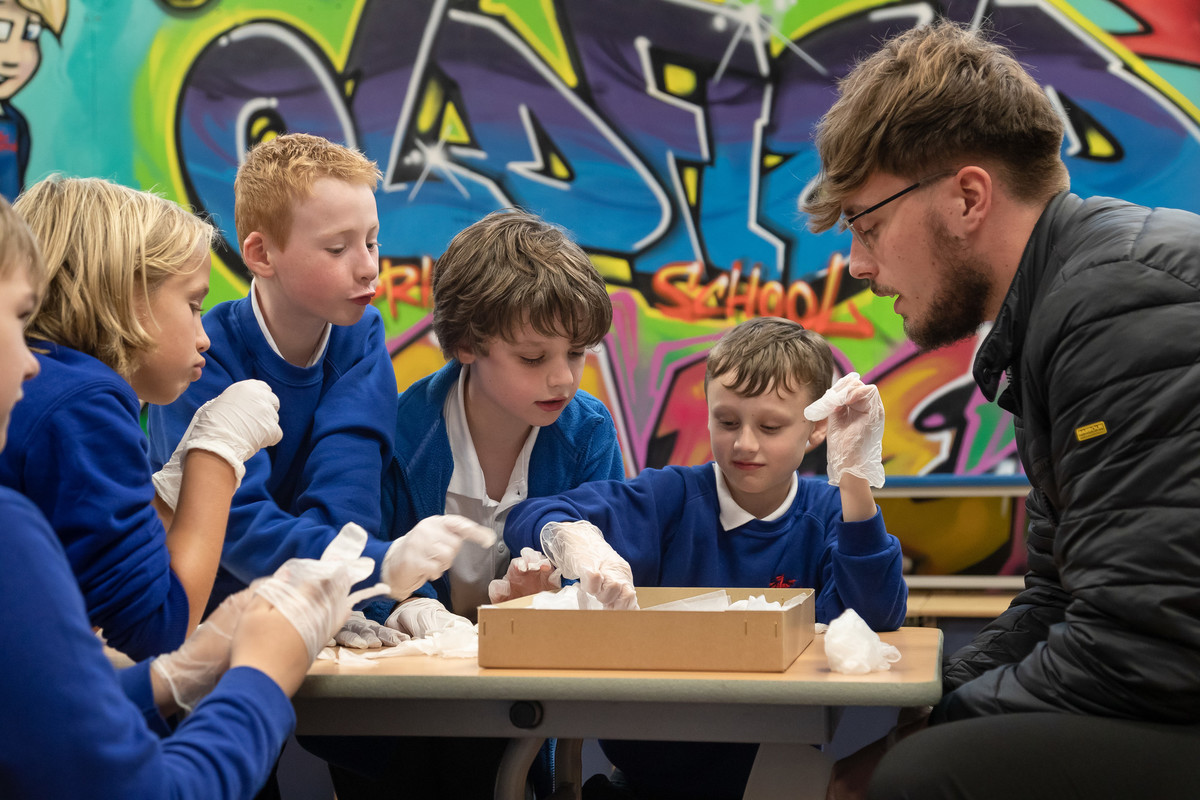 Male teaching student with primary school children doing a classroom activity