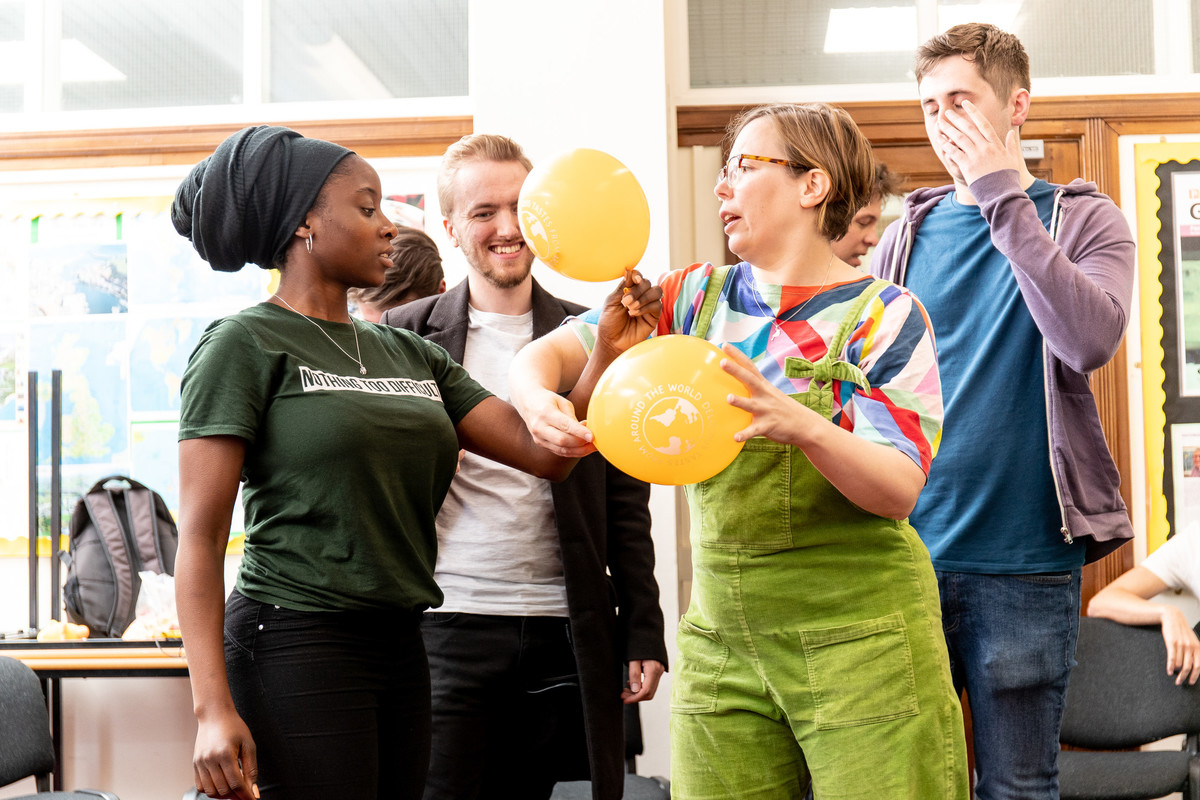 education students working togehter in a group of four holding balloons