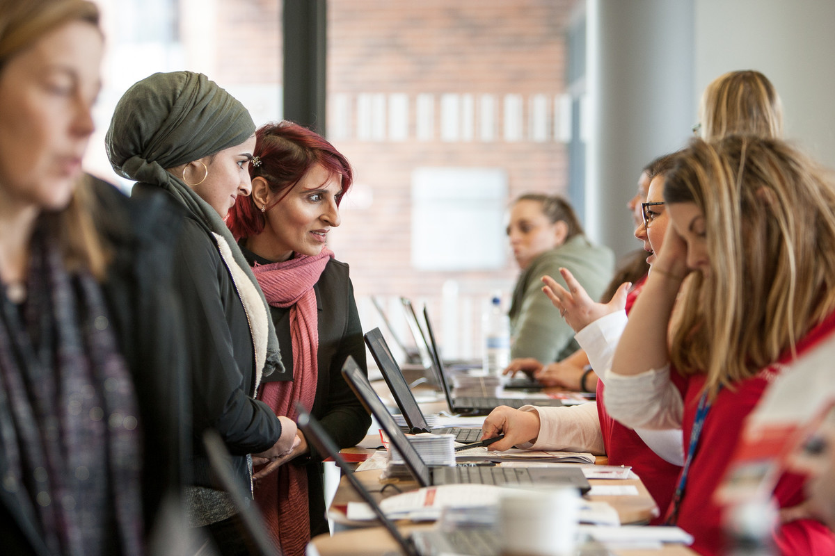 A parent and student at an applicant day, talking to staff across a desk