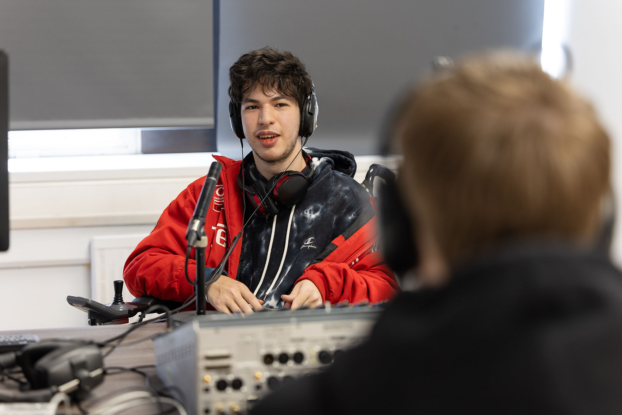Male student recording a podcast in a studio.