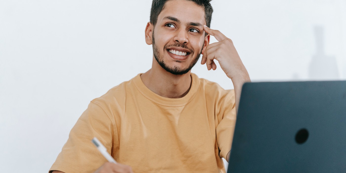 A smiling young man working at his laptop