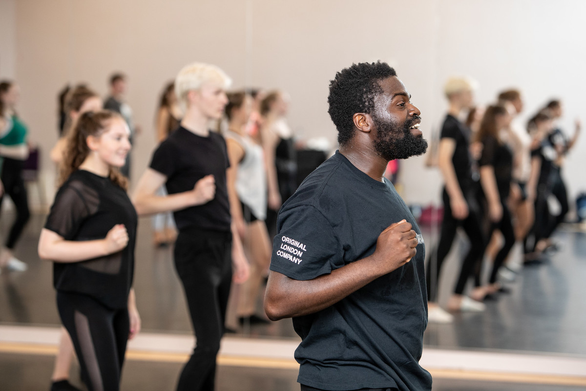 A dance studio with a group of dancers learning to perform on stage.