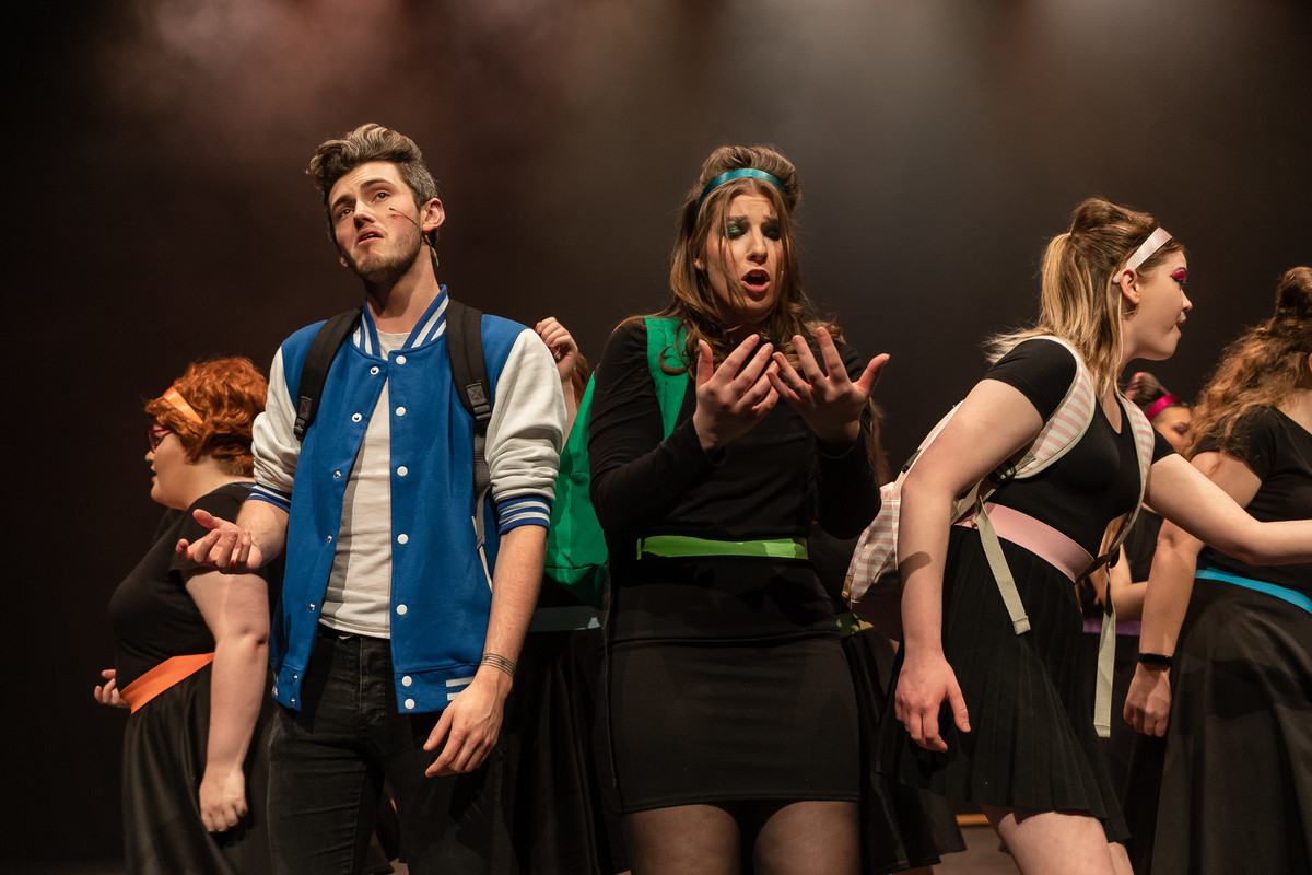 A group of performing arts students on theatre stage with background lighting.