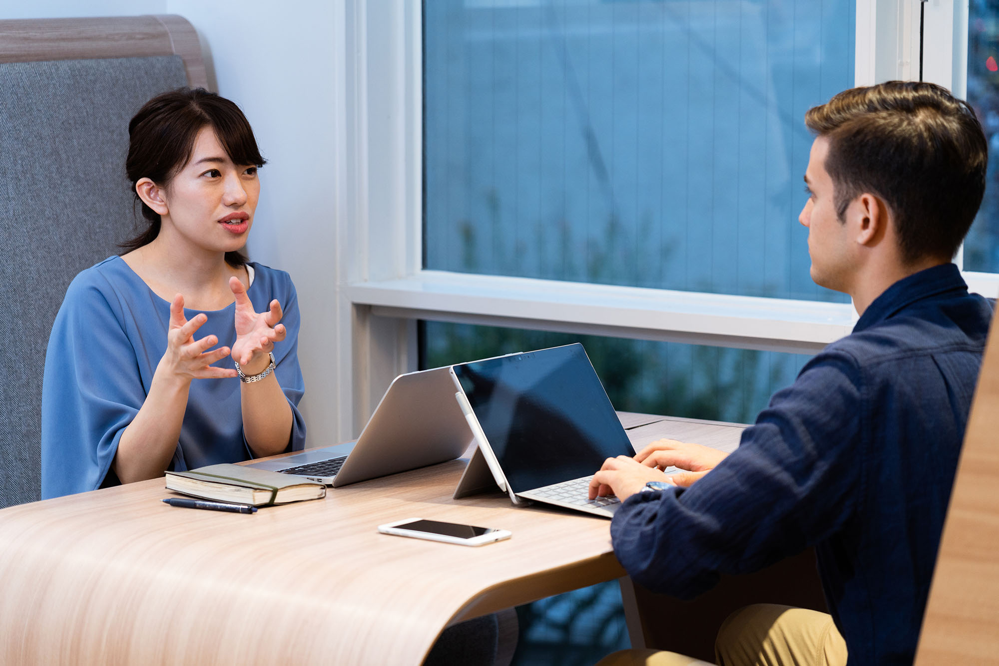 Two business people having a discussion while one is typing up on their tablet